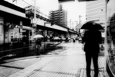 Woman standing on wet street in city during rainy season