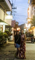 Portrait of smiling young woman standing on street at night