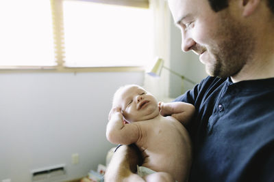 A new dad holds his newborn baby boy while he stretches