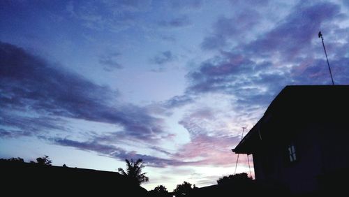 Low angle view of silhouette house against sky