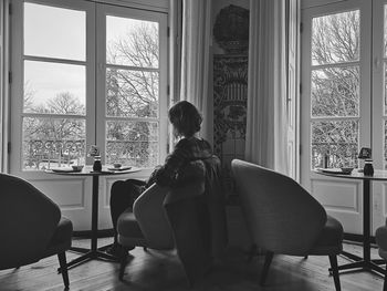 Rear view of woman sitting on chair at home