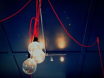 Low angle view of illuminated lighting equipment hanging at night