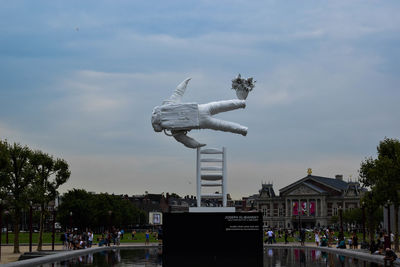 View of sculpture in city against cloudy sky