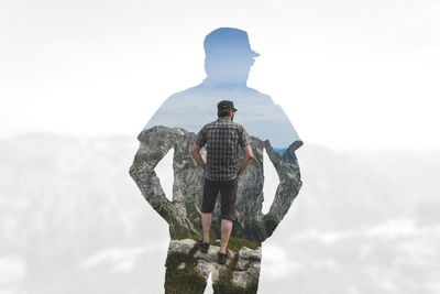 Rear view of man standing on mountain against sky