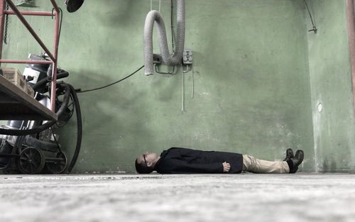 Low section of man sleeping on street in city