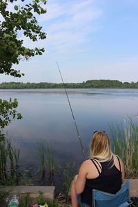 Rear view of young woman fishing at lake