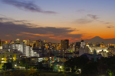 Illuminated cityscape against sky during sunset