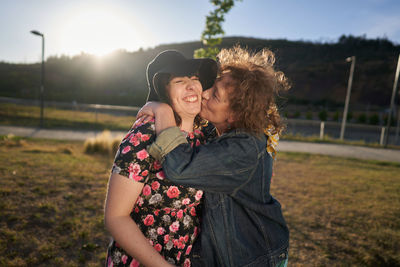 A beautiful latina mother kisses her daughter in a park near the city