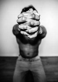 Close-up of man with hands clasped against wall