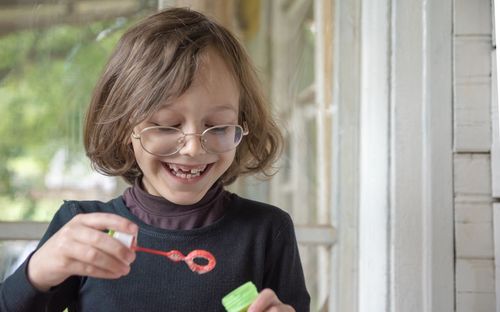 Close-up of cheerful boy blowing bubbles at home