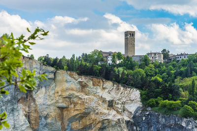 Plants growing on rocks by building against sky