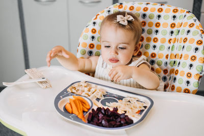 Babys first solid food. solid food for little child 6 months old. cute smiling baby girl in high