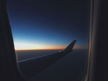 Airplane wing against clear blue sky seen through window