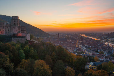 Townscape and trees against sky during sunset