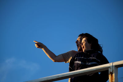 Man pointing with woman against blue sky