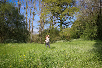 Young woman enjoying amidst plants on field