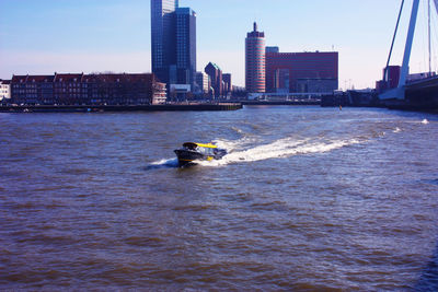 Boat in sea by buildings against sky in city