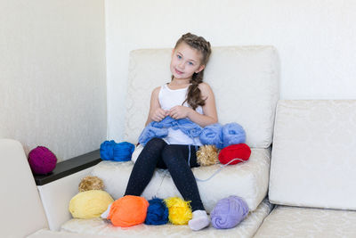 Portrait of smiling girl with wool sitting on sofa at home