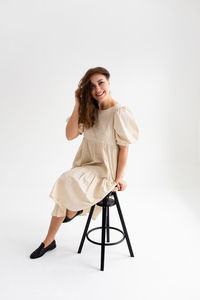 Portrait of young woman standing against white background