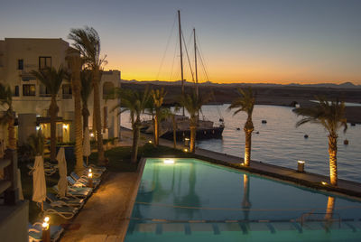 Sailboats in swimming pool against sky at sunset