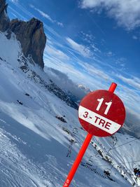 Information sign on snowcapped mountain against sky