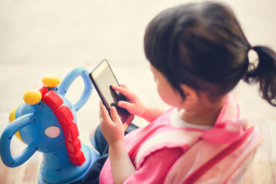 High angle view of girl using smart phone while carrying backpack at home