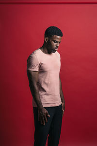 Young man looking away against red background