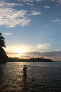 Silhouette person on shore against sky during sunset