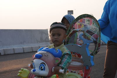 Full length of boy sitting on toy against sky