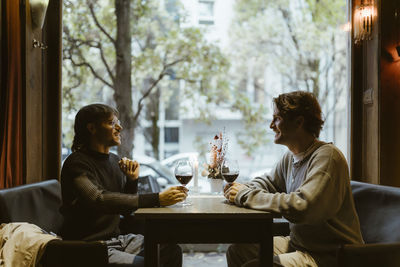 Smiling gay couple having wine while sitting at table in restaurant