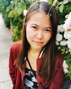 Portrait of smiling young woman standing by flowers