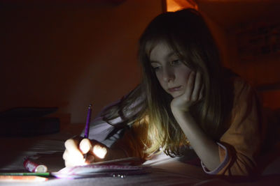 Close-up of girl writing in paper on table at home