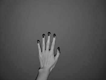 Cropped hand of woman with painted nails against wall