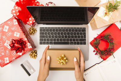 Cropped hand of woman using laptop on table