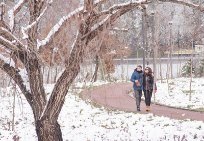 Man and woman walking on snow covered tree