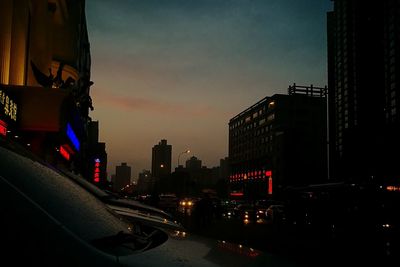 City street amidst buildings against sky at dusk