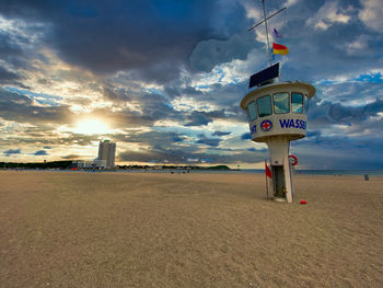 Information sign on beach against sky during sunset