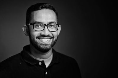 Portrait of smiling young man against black background