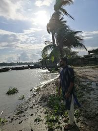 Man standing by palm tree against sky