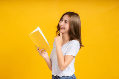 Portrait of a smiling young woman against yellow background