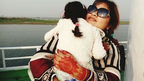 Mother embracing her daughter in boat at lake