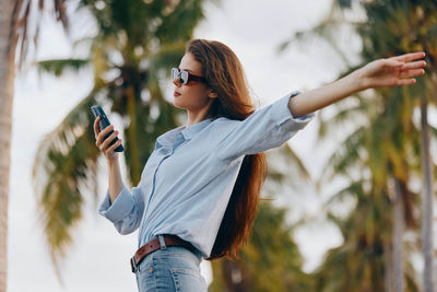 Portrait of young woman standing against plants
