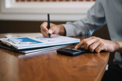 Midsection of man using mobile phone on table