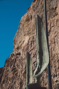 Low angle view of statue against rocky mountain at hoover dam