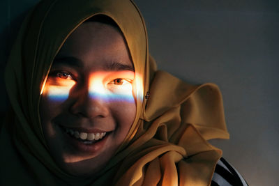 Close-up portrait of spectrum on girl face against gray background