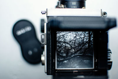 Close-up of vintage camera photographing bare trees during winter