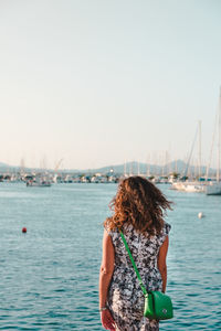 Rear view of woman looking at sea against clear sky