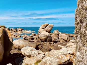 Rocks by sea against blue sky