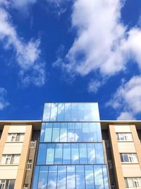 Low angle view of modern building against blue sky
