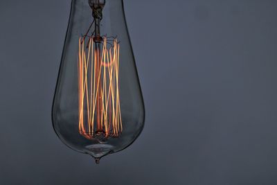 Close-up of illuminated light bulb against wall